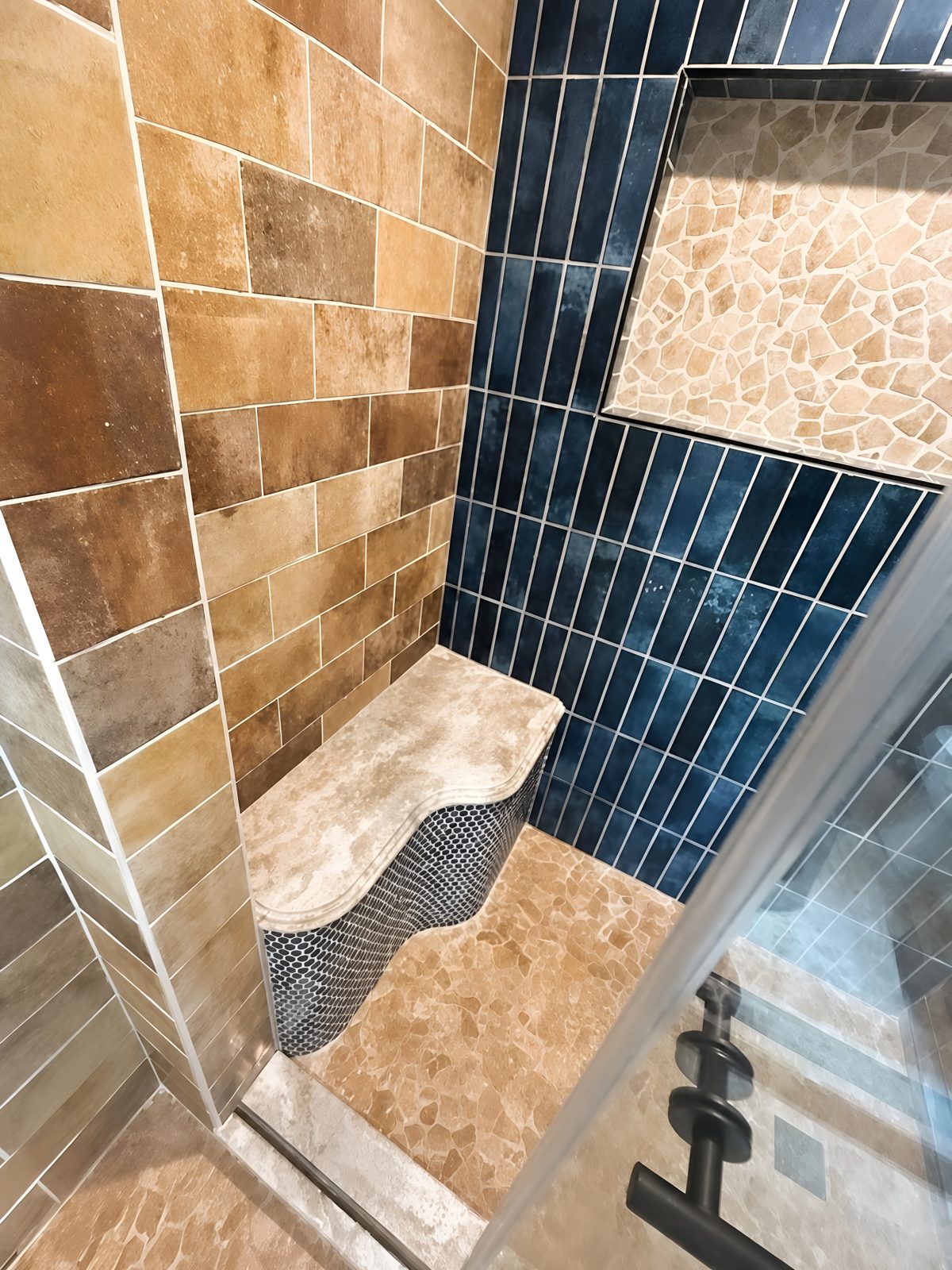 Custom curved tiled shower bench with the dark accent wall behind it