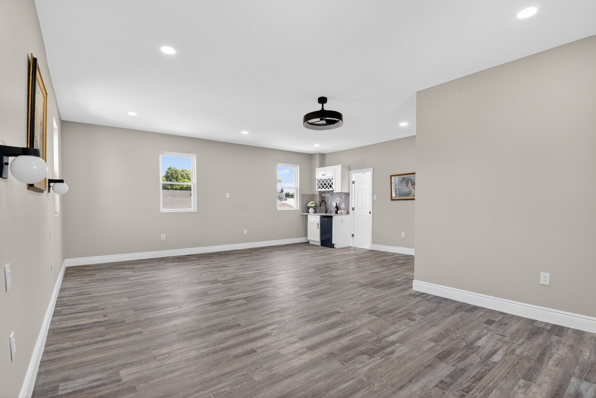 Finished basement renovation with open floor plan, LVP flooring, recessed lighting, and wet bar