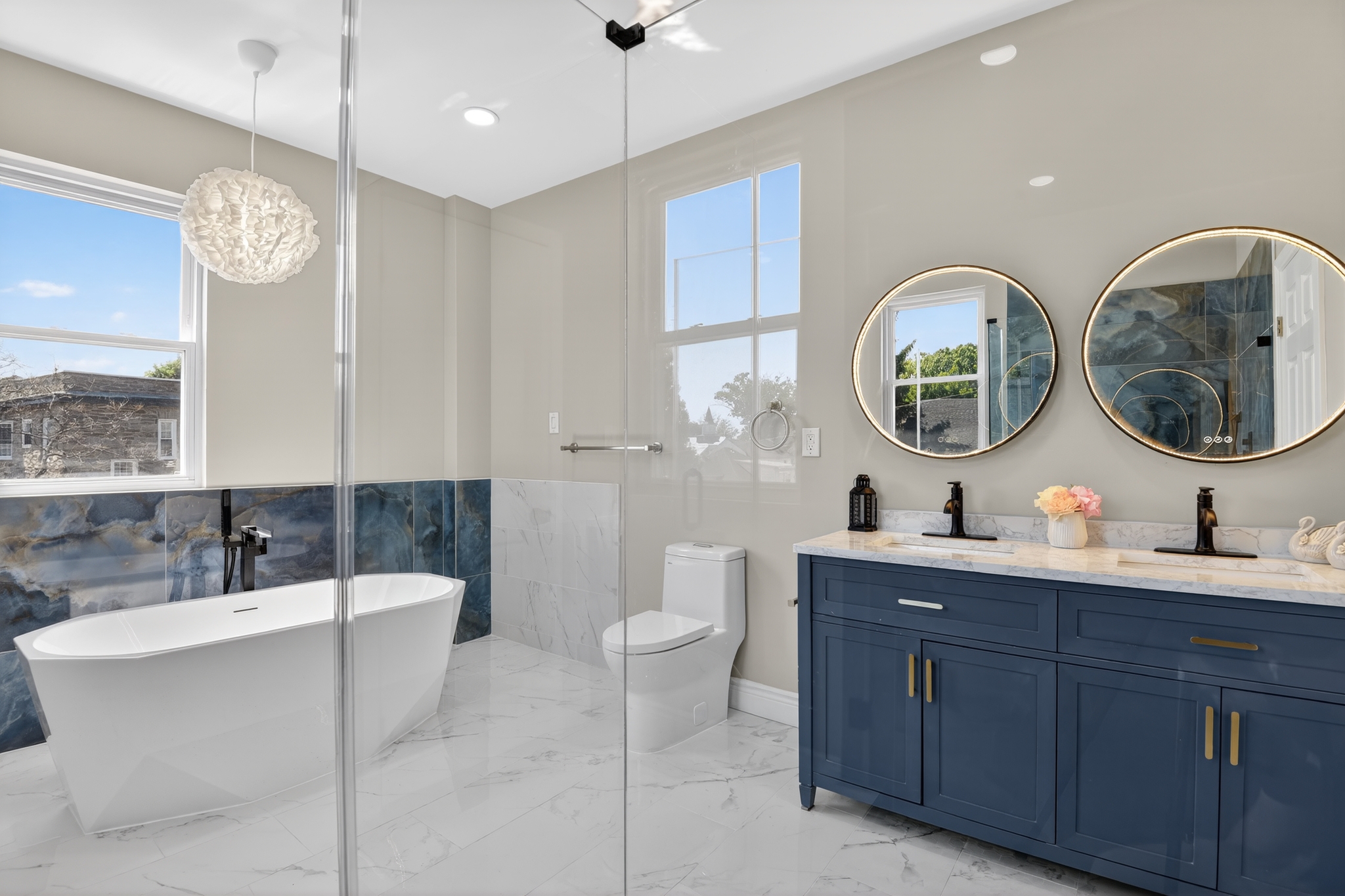 Luxury bathroom remodel with freestanding soaking tub, navy double vanity, and marble tile