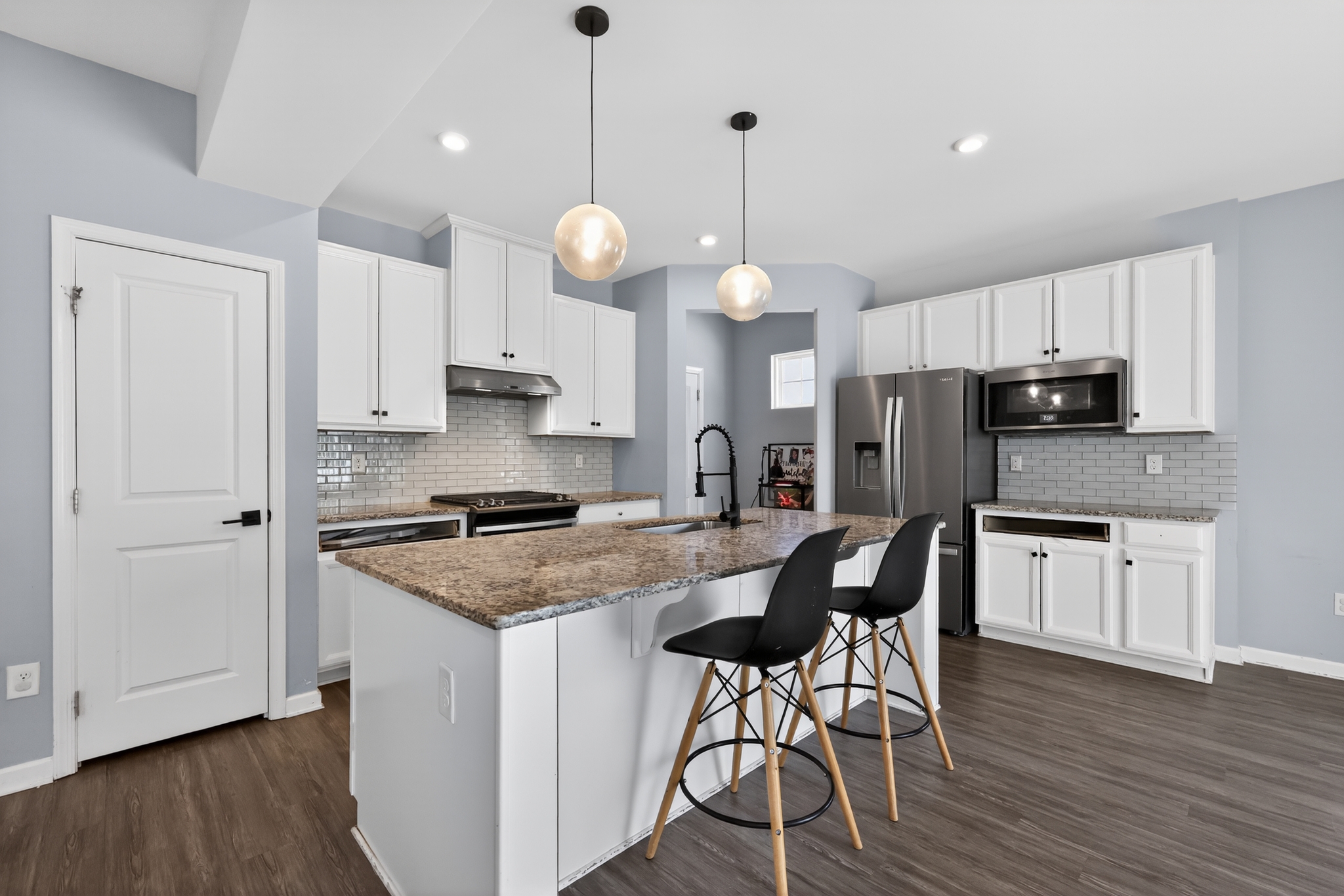Kitchen renovation with white cabinets, granite island, and pendant lighting