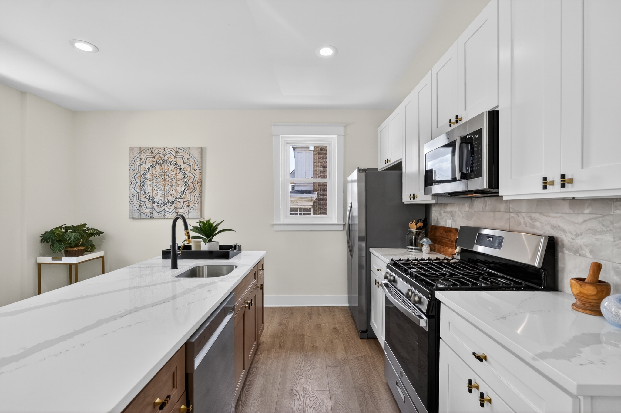 Renovated kitchen with white shaker cabinets, quartz countertops, and walnut island