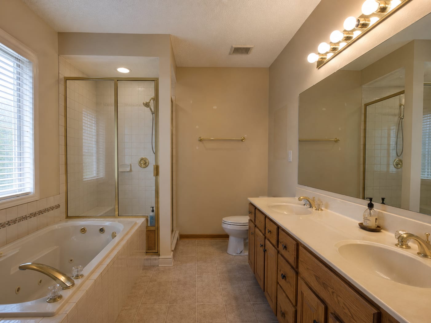 Builder-grade bathroom with worn tub-shower combo and oak vanity